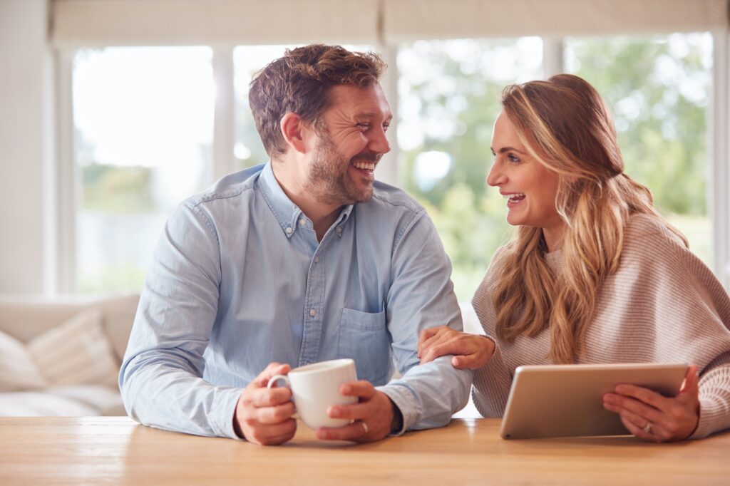 Couple At Home Buying Products Or Services Online Using Digital Tablet